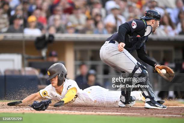 Ha-Seong Kim of the San Diego Padres dives as he scores ahead of the throw to David Fry of the Cleveland Guardians during the third inning of a...