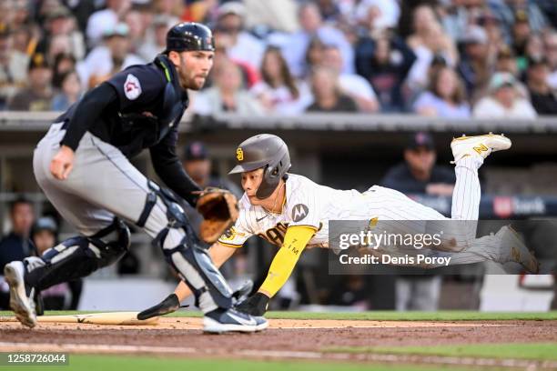 Ha-Seong Kim of the San Diego Padres dives as he scores ahead of the throw to David Fry of the Cleveland Guardians during the third inning of a...