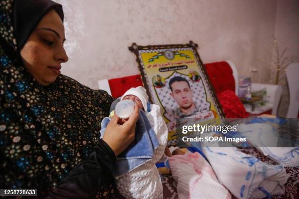 Rasmiya Shamali feeds milk to one of her four newborn babies with a portrait of their father, Palestinian prisoner Ahmed Shamali on the bed. Gaza...