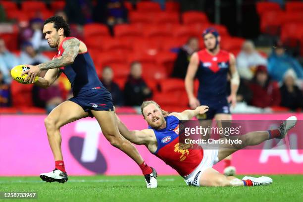 Harley Bennell of the Demons kicks whilst being tackled by Daniel Rich of the Lions during the round 8 AFL match between the Melbourne Demons and the...
