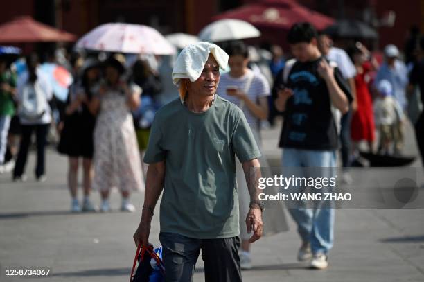 Man shelters under a towel during hot weather conditions in Beijing on June 16, 2023.