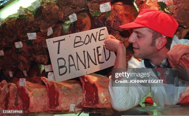 Butcher in London's Smithfield meat market places a notice 17 December on his stall informing customers of the ban on sales of beef on the bone,...