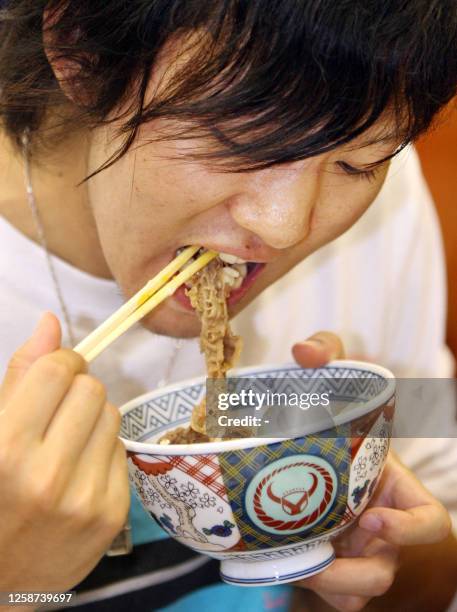 Japanese customer enjoys a bowl of "gyudon", a beef and rice dish commonly referred to as beef bowls, at a Yoshinoya fast food restaurant in Tokyo,...