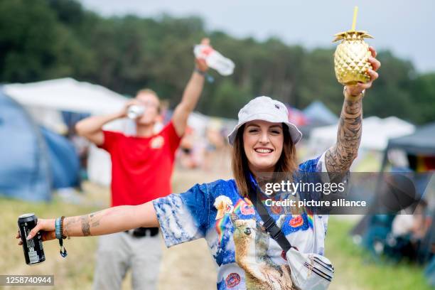 June 2023, Lower Saxony, Scheeßel: Visitor Sarah walks across the Hurricane Festival campground with a beer can and drinking cup. The open-air...