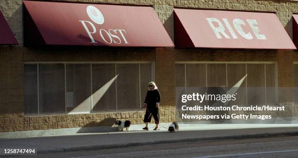 Woman walks her dog as late afternoon sunlight steams across the side of the Rice Lofts garage on Travis St. Tuesday afternoon, November 19, 2002....