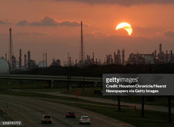 As traffic heads westward toward the Shell Deer Park Refinery on highway 225, the sun, partially eclipsed by the moon, sets Monday night, June 10,...