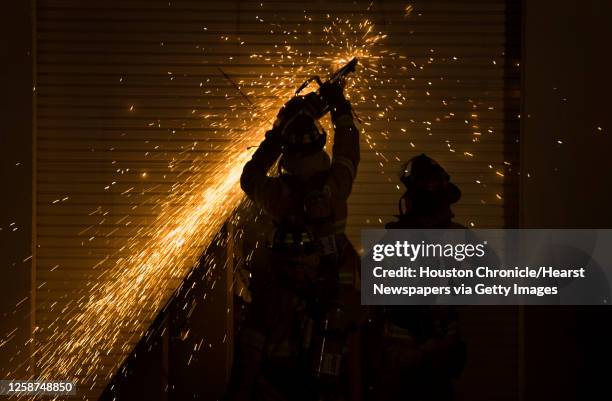 Firefighters use a saw to gain entry into the Iglesia Cristiana Monte Sinai in the Solon Business park on Solon Road in Northwest Harris County while...