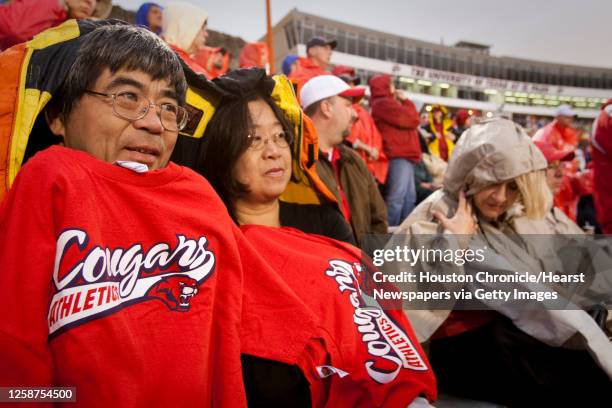 Walter and Samantha Kwan of Houston bundle against a chilly rain to watch the Houston Cougars take the field against UTEP at the Sun Bowl Saturday,...