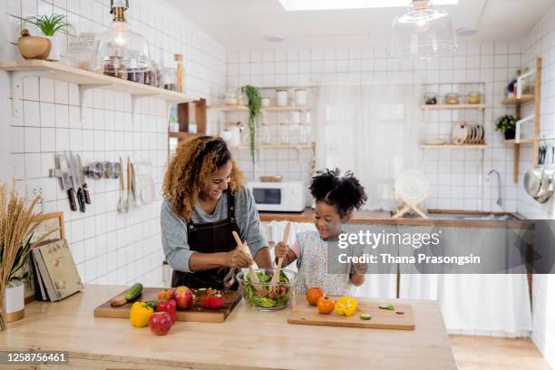 girl learning to prepare meal from mother - mother and daughter cooking photos et images de collection