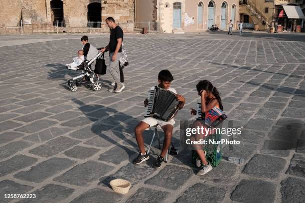 Two children are playing accordion at the Old Venetian Port of Chania in Chania, Crete Island, Greece on June 16, 2023. Chania's Venetian Harbour was...