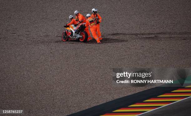 The motorbike of Repsol Honda Team's Spanish rider Marc Marquez is pushed out of the gravel by track marshals during the qualifying session for the...