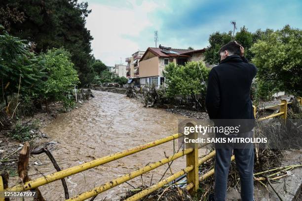 Man stands on a bridge covered with branches, brought by flood water, following floods caused by overnight heavy rainfall in Thessaloniki on June 17,...