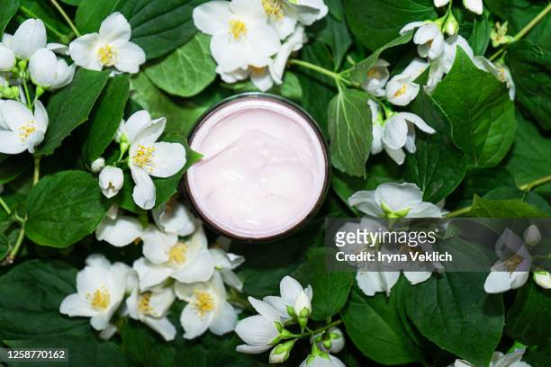 natural cosmetic product, beauty cream for care of skin and face with jasmine flowers pattern. - biological product stock pictures, royalty-free photos & images