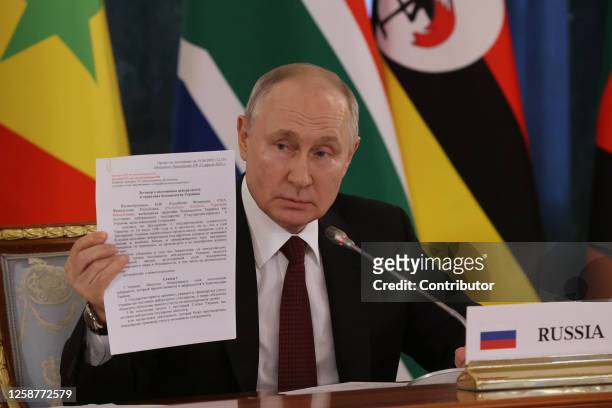 Russian President Vladimir Putin holds a page of the Minsk Agreement during his meeting with African leaders at the Konstantin Palace in Strelna on...