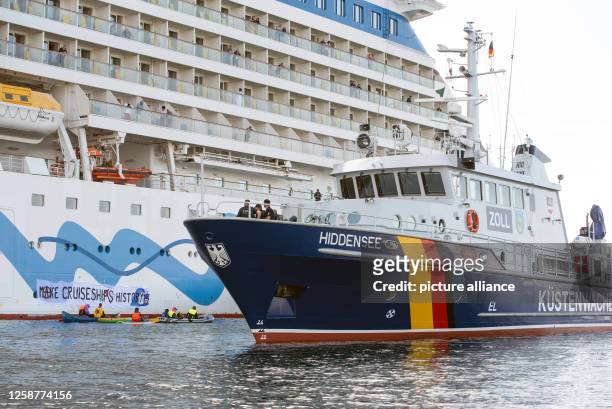 June 2023, Mecklenburg-Western Pomerania, Rostock-Warnemünde: Climate activists on canoes and inflatable boats try to prevent the cruise ship "Aida...