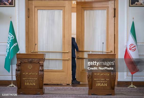 Saudi official stands at a door of a conference hall next to an Iran flag , and a Saudi Arabia national flag in Tehran's Foreign Ministry building,...