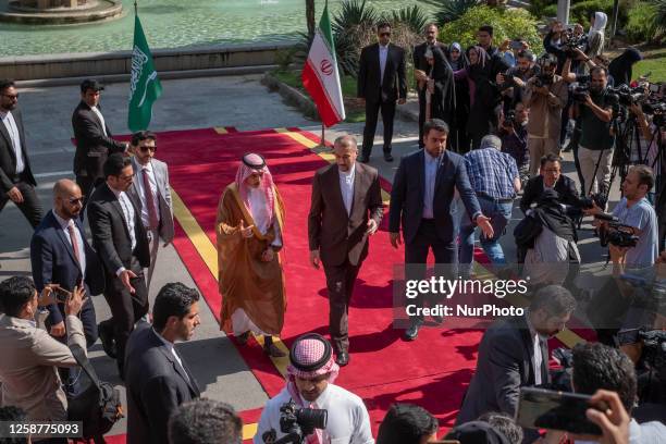 Iran's Foreign Minister Hossein Amir Abdollahian walks with his Saudi counterpart Faisal Bin Farhan during an official welcoming ceremony in Tehran's...