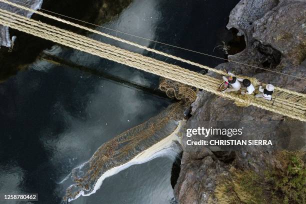 Aerial view showing people from different communities participating in the annual renovation of the Q'eswachaka rope bridge, as the old one drifts...