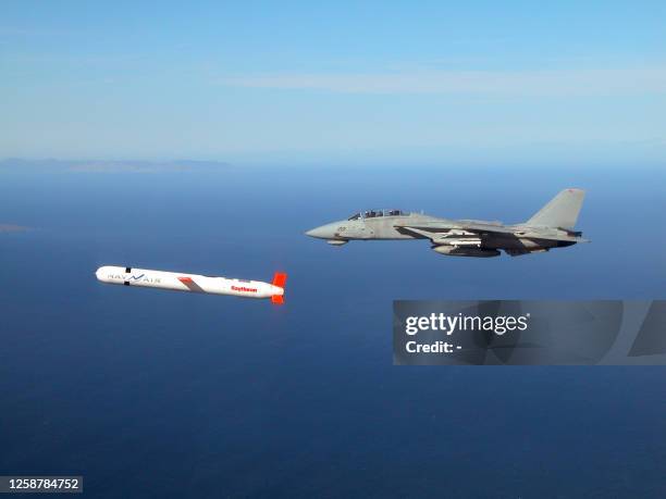 Tactical "Tomahawk" Block IV cruise missile is escorted by a Navy F-14 "Tomcat" fighter during a controlled test over the Naval Air Systems Command...