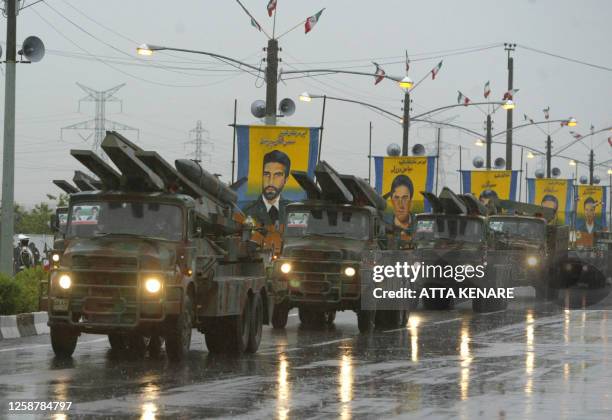 Iranian military vehicles carrying Nazeat ground-to-air missiles drive past portraits of Iranian soldiers killed during the 1980-88 war with Iraq,...