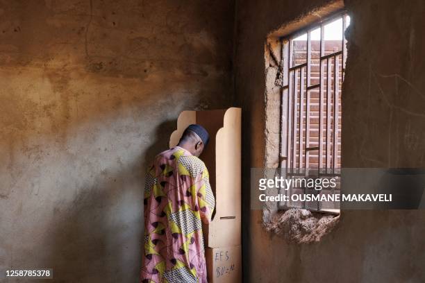 Voter marks his ballot at a voting booth as polls open in Mali's referendum in Bamako on June 18, 2023. Malians head to the polls to vote in a...