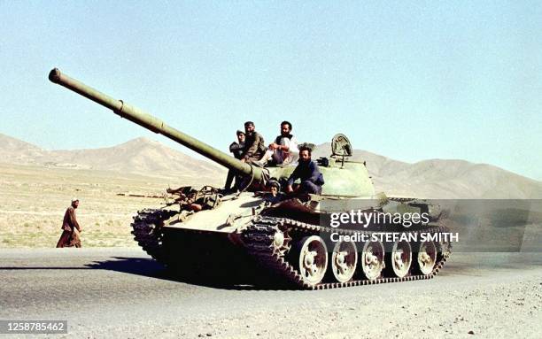 Churning out clouds of black smoke from its ageing Soviet engine, an Afghan Taliban operated tank carrying reinforcements speeds to the frontlines...