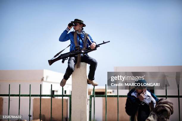 Rebel fighter uses binoculars to monitor the skies over the flashpoint town of Ras Lanuf on March 8 as Libya's air force carries out raids, on this...