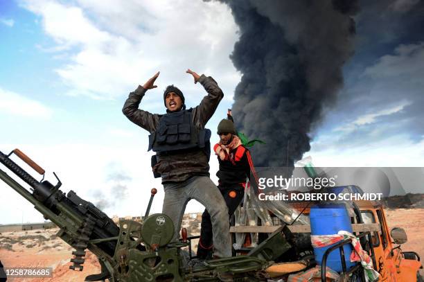 Libyan rebel fighters react during clashes with forces loyal to leader Moamer Kadhafi, just few kilometers outside the oil town of Ras Lanuf on March...