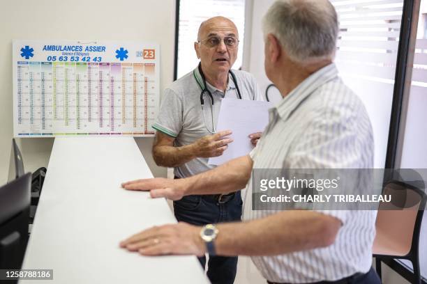 General practitioners Pierre Le Tinnier and Yves Carcaillet doctors who were retired and have returned to work, speak in between consultations at...