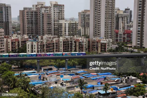 Metro train moves past buildings and slums, in Mumbai, India, 18 June, 2023.