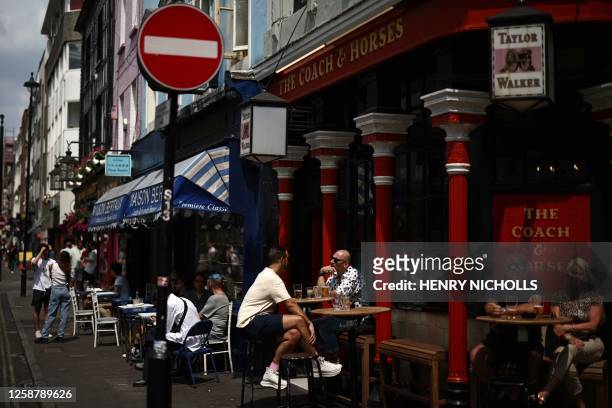 Members of the public enjoy a drink in the sunshine outside a pub in the Soho area of London on June 18, 2023. Recent data showed UK inflation slowed...