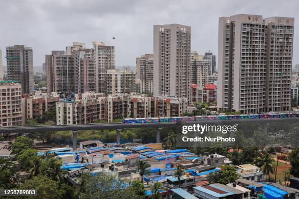 Metro train moves past buildings and slums, in Mumbai, India, 18 June, 2023.