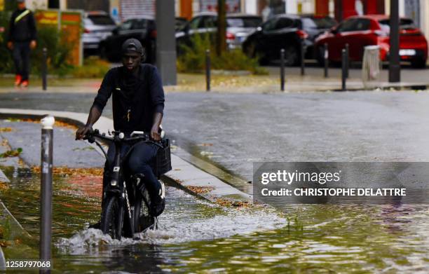 Man rides a bicycle in a street flooded by heavy rain in Paris, on June 18, 2023.