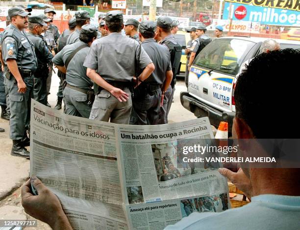 Un habitante de la favela Rocinha lee un periódico con noticias sobre los enfrentamientos en su barrio, cerca de integrantes de la Policia...