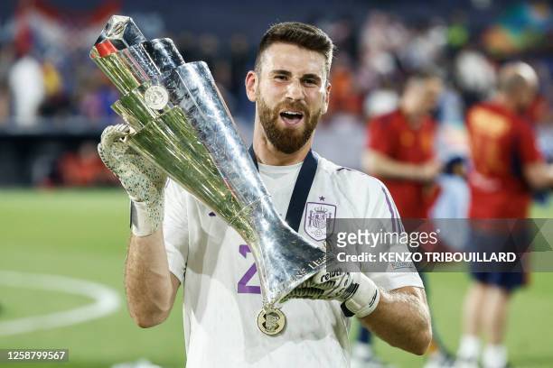Spain's goalkeeper Unai Simon holds the UEFA Nations League cup as he celebrates after winning the penalty shootouts and the UEFA Nations League...