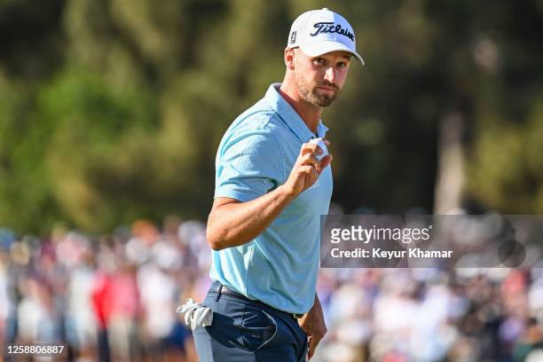 Wyndham Clark waves his ball to fans after making a birdie putt on the 14th hole green during the final round of the 123rd U.S. Open Championship at...