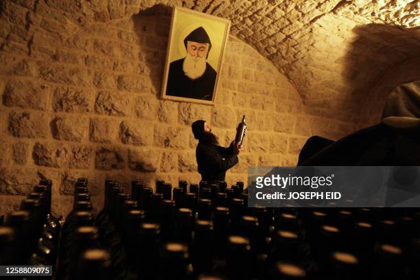 Maronite monk picks a bottle of organic wine at the reserve of the monastery of Mar Mussa in the mountains northeast of Beirut on January 14, 2010....