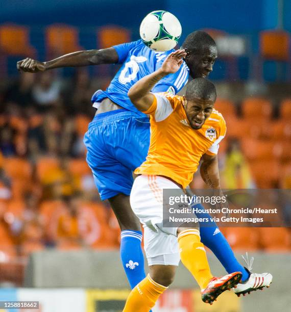 Houston Dynamo midfielder Corey Ashe goes up for a header against Montreal Impact defender Hassoun Camara during the first half of a MLS playoff...