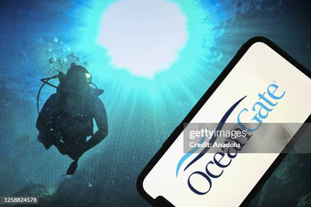 The logo of "OceanGate" is displayed on a mobile phone screen in front of an underwater photo background in Ankara, Turkiye on June 19, 2023.