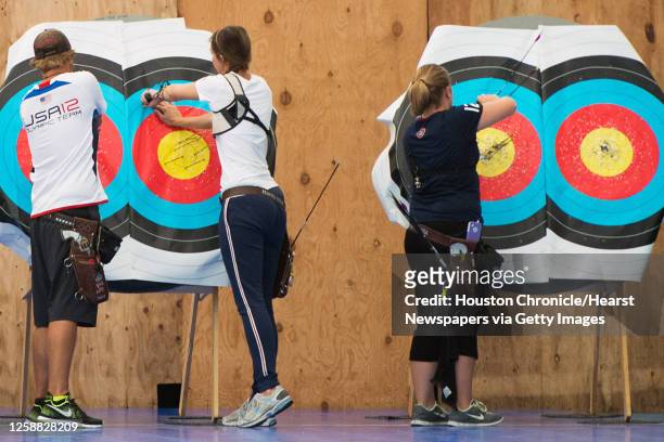 Archers, from left, Brady Ellison, Jennifer Nichols, and Miranda Leek remove arrows from targets during training in preparation for the 2012 Summer...