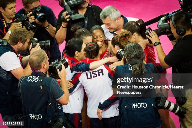 Gabby Douglas, facing, celebrates with teammates as photographers crowd around the U.S. The after their scores on their final apparatus gave them the...