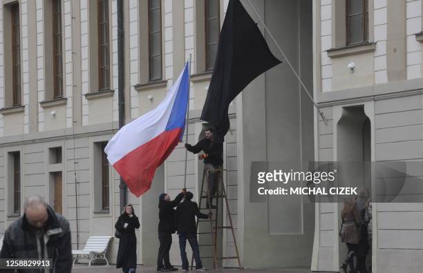 Black flag waves as a man hangs a Czech national flag on December 18, 2011 at Prague Castle to commemorate the death of former Czech President Vaclav...