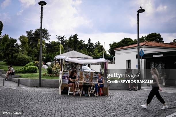 Members of Greece's new Green and Purple alliance formed for the upcoming elections, sit at one of their party's kiosk in Athens on June 16, 2023. A...
