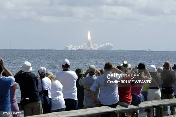 People on a public pier in Titusville, Florida, watch as the space shuttle Atlantis lifts off 09 September 2006 across the Indian River from launch...