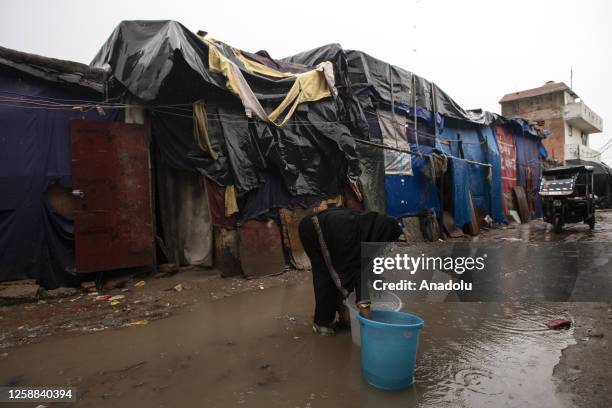 Rohingya Muslim refugee woman transfers water from a bucket placed to collect rainwater in an alleyway at a refugee camp, ahead of the occasion of...