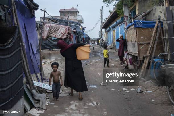 Rohingya Muslim refugee woman carries water container filled from a tanker outside at a refugee camp, ahead of the occasion of World Refugee Day in...