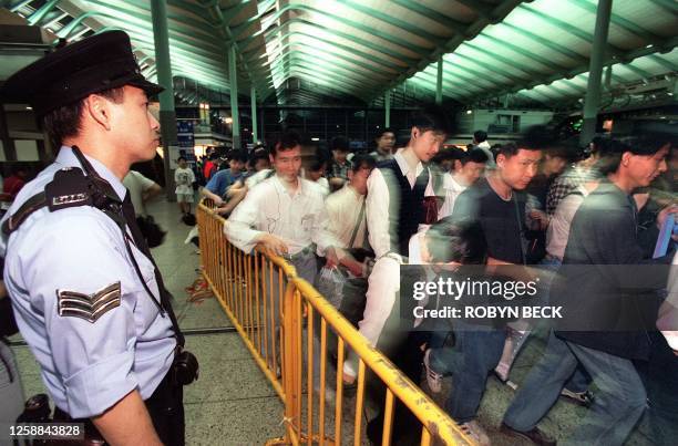 Policeman at Hong Kong's Hung Hom Railway station keeps an eye on the thousands of people queuing to buy tickets for cross-border train into China to...