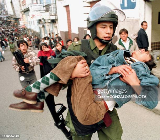 An anti-riot police carries a girl injured by a rock thrown by a protester 05 February in La Paz. Un oficial de la policia antimotines lleva en...