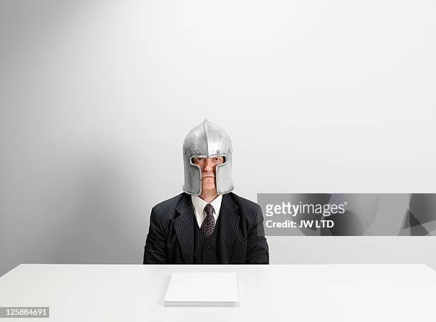 portrait of mature businessman wearing helmet - warrior stock-fotos und bilder