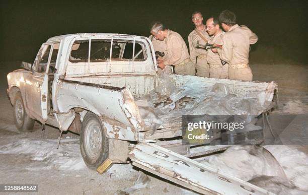 Iraqi policemen check a car after a remote-control bomb placed in it exploded late 17 October as a bus carrying Mujahedeen members entered the town...